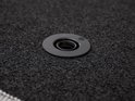 Œillet de fixation en plastique gris sur un tapis noir.