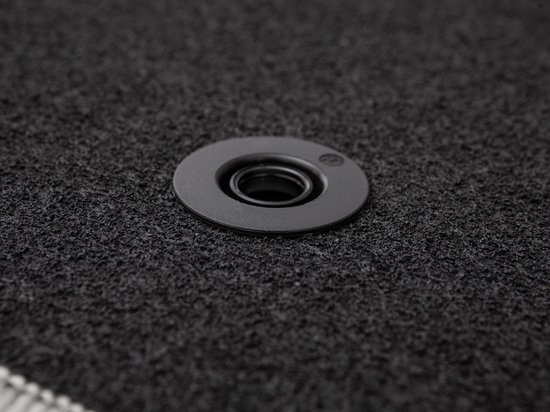 Œillet de fixation en plastique gris sur un tapis noir.