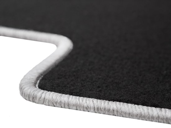 Tapis noir avec passepoil gris, gros plan sur le bord.