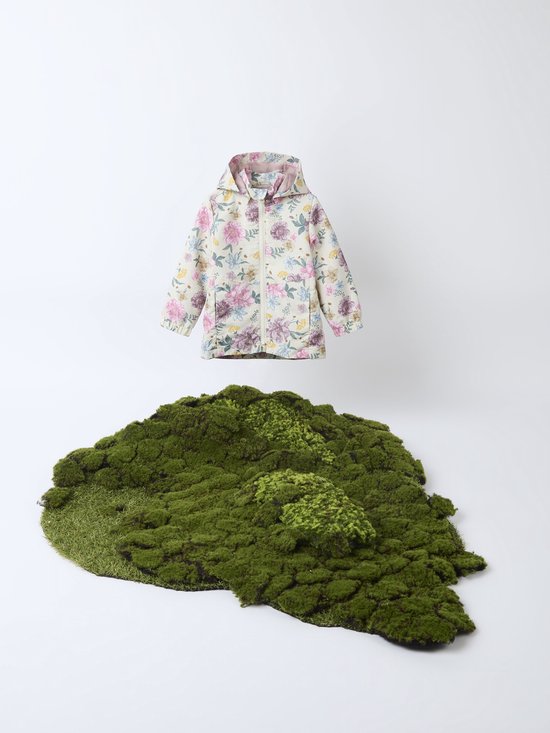 Meisjesjas met bloemenprint zweeft boven een hoop mos.