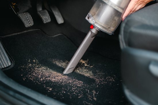Autobinnen met zwarte vloermat die wordt schoongemaakt met een kruimeldief.