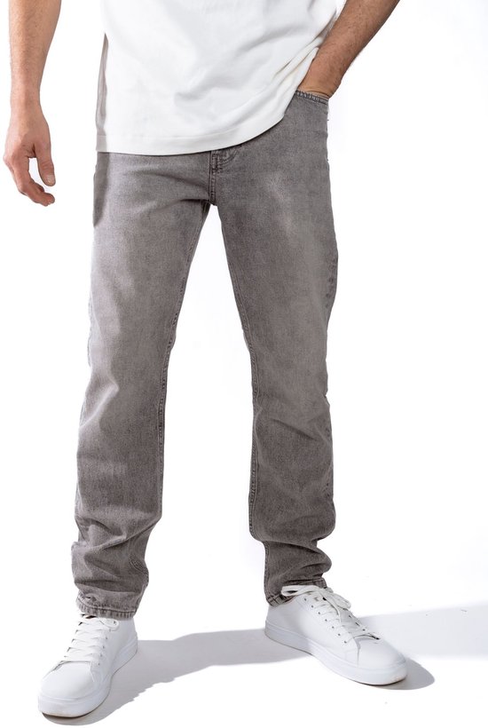 Detailopname van een man in een witte t-shirt en grijze jeans.