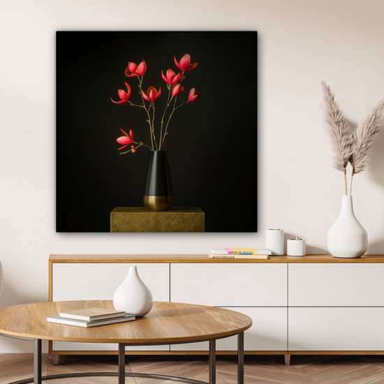 Een zwart en goudkleurig vaasje met rode bloemen op een gouden sokkel, tegen een zwarte achtergrond.
