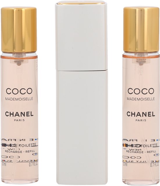 Drie flacons Coco Mademoiselle Eau de Toilette van Chanel met gouden dopjes, naast een zilverkleurige verstuiver.