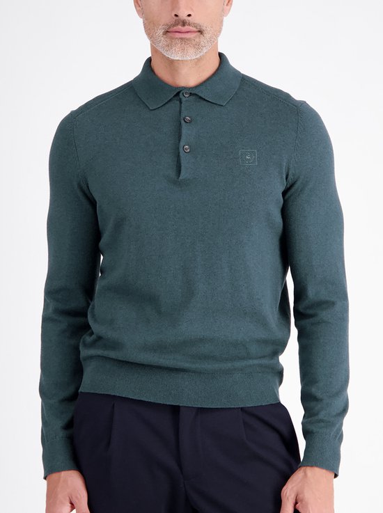 Voorkant van een man in een donkergroene trui met lange mouwen, kraag en logo, gedragen met donkere broek.