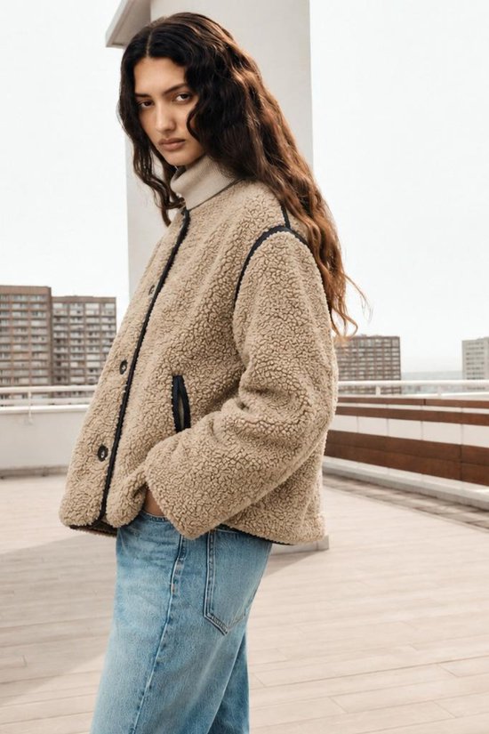 Beige teddy jas van ONLY met donkerblauwe biesjes en knoopsluiting, gedragen door model met lichte jeans.