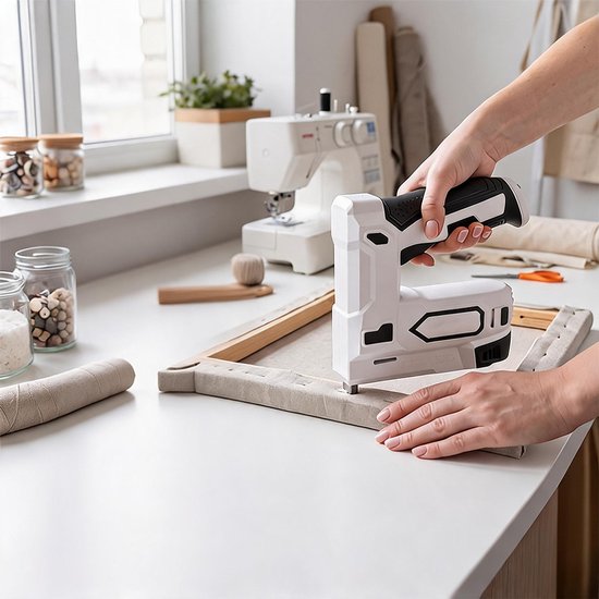 Vrouw gebruikt een wit-zwart nietpistool om canvas strak te trekken op een houten frame.