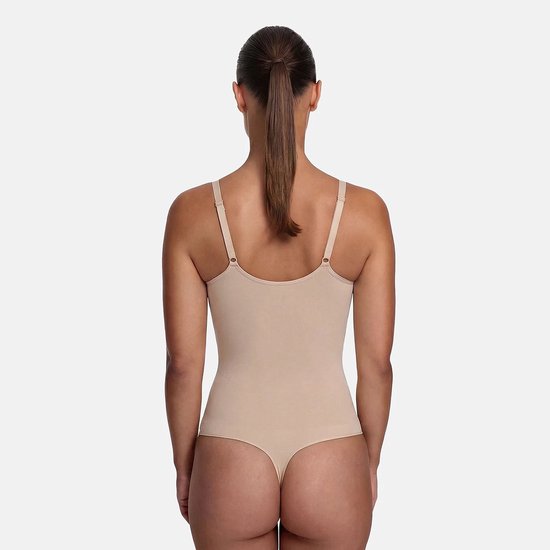 Achteraanzicht van een beige naadloze string-bodysuit met verstelbare bandjes op een model met een paardenstaart.