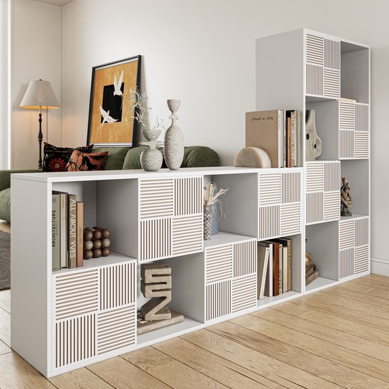 Lage witte opbergkast, deels gevuld met boeken en decoratie, met enkele vakken met verticale ribbeldecoratie.