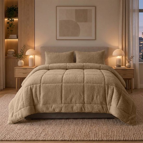 Een taupe teddy dekbed met ruitpatroon en twee bijpassende kussens liggen op een bed.