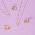 Gouden kettingen en hartvormige hangers met letters A, K, L, M en S op een lila achtergrond.