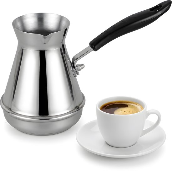 Roestvrijstalen Turkse koffiepot met zwarte handgreep naast een kopje koffie op een schoteltje.