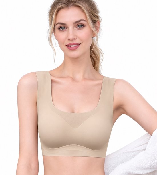 Vrouw met een lichte huid die een beige naadloze sportbeha draagt. Haar schouders zijn zichtbaar.