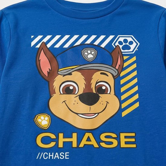 Close-up van Chase van Paw Patrol met pet, blauwe tekst 'CHASE' en gele strepen op een blauwe pyjamatop.