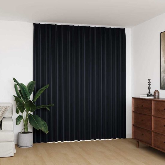 Verduisterend zwart gordijn met haken, 290x245 cm. De plooien vallen tot op de houten vloer.