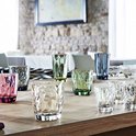 Une collection de verres colorés et transparents avec un motif à facettes sur une table.