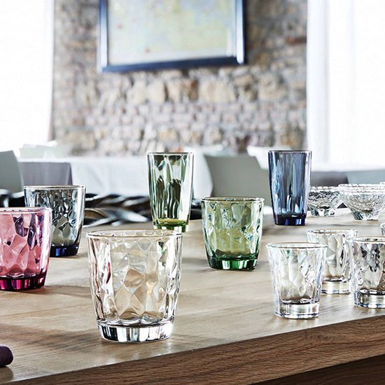 Une collection de verres colorés et transparents avec un motif à facettes sur une table.