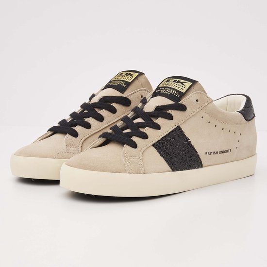 Paar beige suède lage sneakers met zwarte glitterstreep, zwarte veters en logo op de tong.