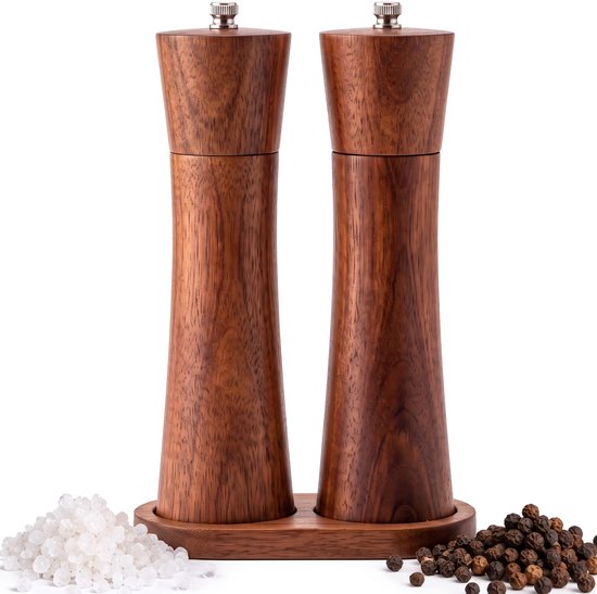 Set van twee houten peper- en zoutmolens in een houten houder, met zoutkristallen en peperkorrels ernaast.