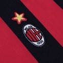 Close-up van AC Milan-clubembleem en een gouden ster op een rood-zwarte gestreepte achtergrond.