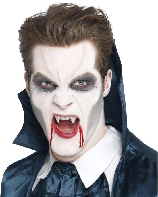 Man met vampier-make-up, witte huid, bloederige slagtanden en donkere ogen.