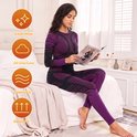 Vrouw zittend op een bed, lezend in een paarse en zwarte thermische set. Iconen voor 'Clean Wear', 'All-Day Cozy', 'Smooth Fit', 'Breath Fit'.