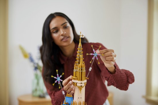 Een vrouw bouwt het LEGO Disney Kasteel, en plaatst een gouden ster-vormig stuk op de top.
