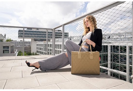 Vrouw met krullend blond haar, zittend op een balkon, met een beige Reisenthel shopper naast haar.