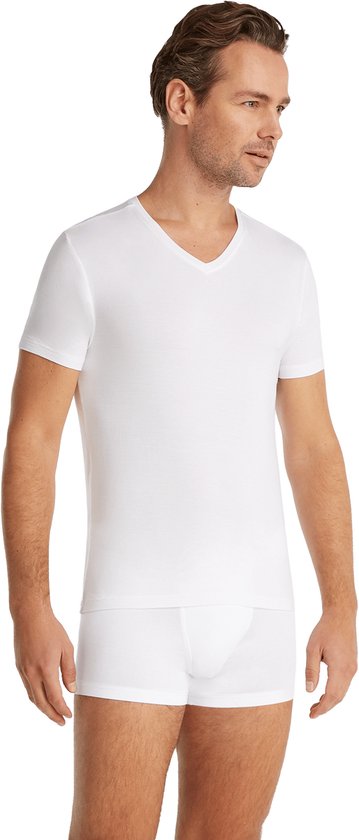 Man in wit V-hals T-shirt en witte boxershorts, staand naar rechts gedraaid.