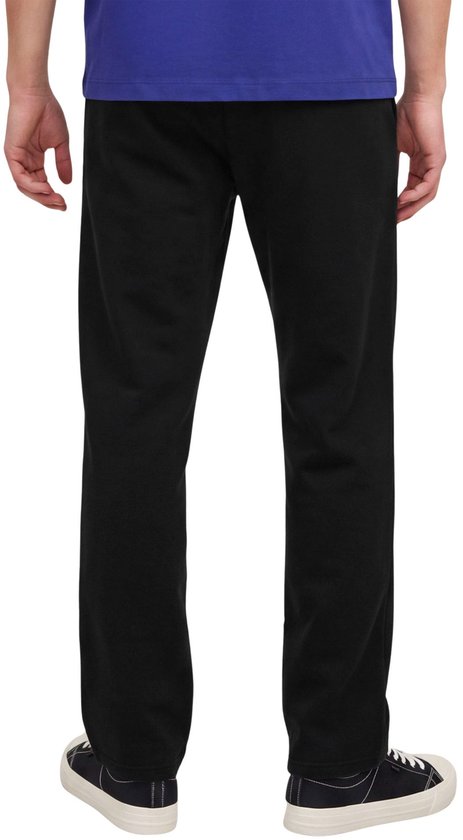 Achteraanzicht van een model in een zwarte joggingbroek gecombineerd met een blauw T-shirt en zwarte sneakers.