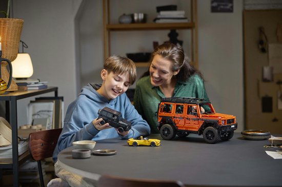 Een vrouw en een jongen bekijken LEGO auto's, waaronder een oranje Mercedes-Benz G 500.