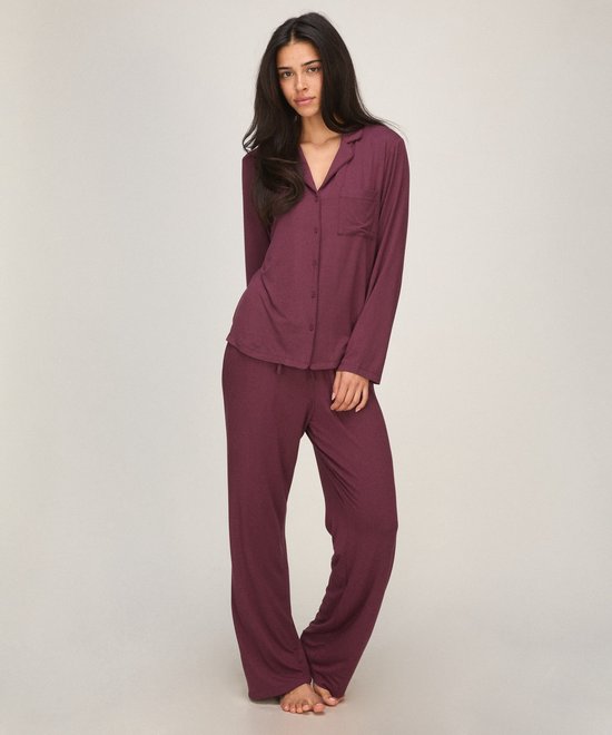 Model draagt een paarse pyjamaset bestaande uit een jasje met knopen en een lange broek.