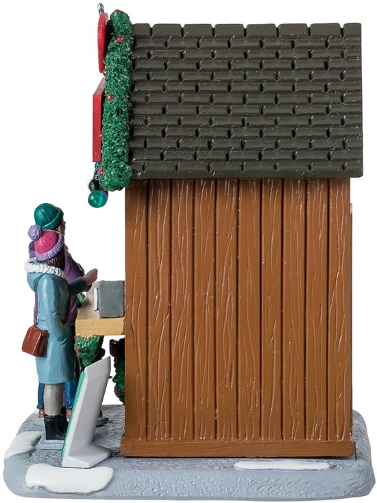 Zijaanzicht van een houten kerstkraam met een klant die bij het loket wacht op een besneeuwde ondergrond.