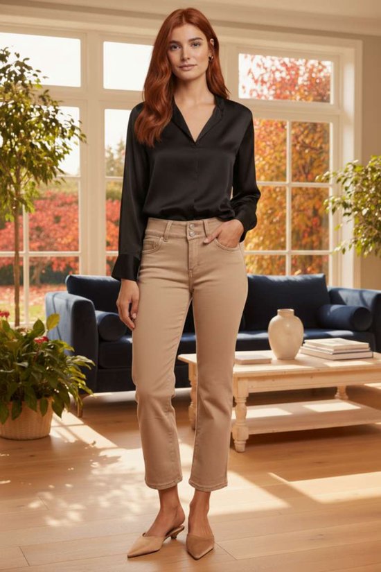 Model draagt een zwarte satijnen blouse en een beige enkelbroek met dubbele knoopsluiting en hakken.