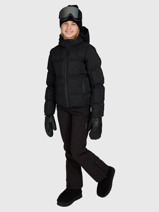 Model in een volledig zwarte Brunotti-skiset met jack, broek, skibril en muts.