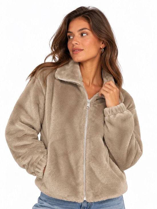 Model in een beige, zachte, gebreide jas met rits en kraag.