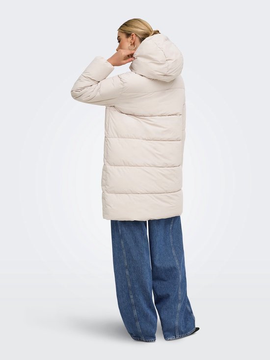 Model van achteren gezien met een beige pufferjas en wijde blauwe jeans.
