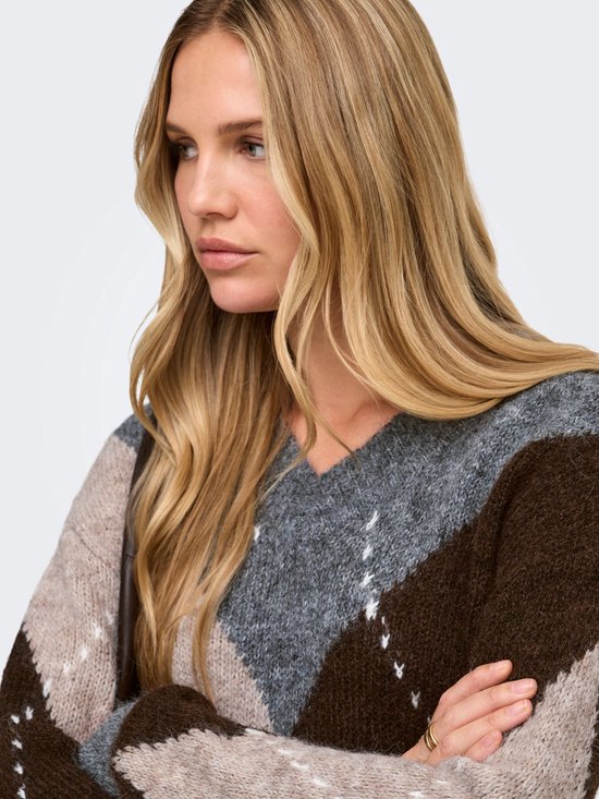 Close-up van model met lang blond haar, draagt een v-hals trui met argyle-patroon in grijs, bruin en beige.