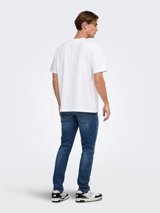 Achterkant van een model in een wit T-shirt, donkerblauwe slim-fit jeans en zwart-witte sneakers.