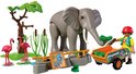 Grijze PLAYMOBIL olifant met dierenverzorger in gele outfit die een kruiwagen met groen duwt, flamingo's, boom en informatiebord.