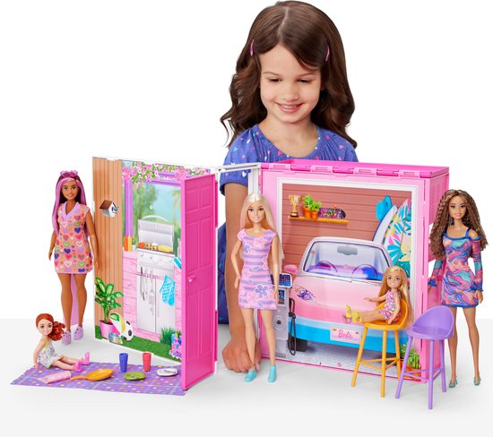 Een kind speelt met Barbiepoppen en een openklapbaar vakantiehuis met keuken en garage.