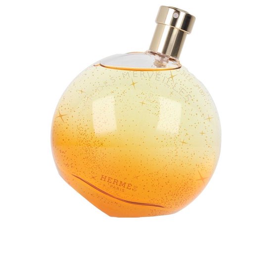 Elixir des Merveilles Eau de Parfum. Rond parfumflesje met goudkleurige dop, oranje-geel glas met fijne gouden spikkels.