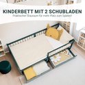 Groen kinderbed met twee opengewerkte lades, een matras en kinderkamer decoratie.