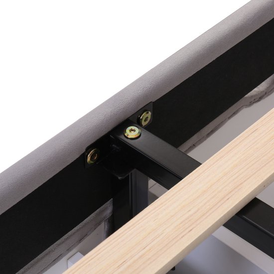 Bevestigingsdetails van de metalen en stoffen constructie van een grijs bedframe met houten latten.