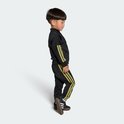 Jongetje in zwart trainingspak met gouden strepen en Adidas sneakers.