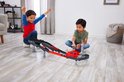 Twee jongens spelen met een rode en grijze Hot Wheels F1 racebaan, één juicht.
