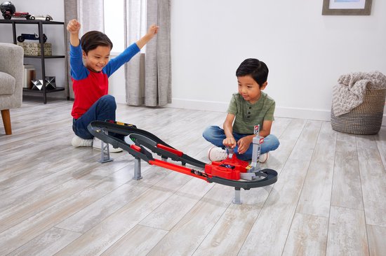 Twee jongens spelen met een rode en grijze Hot Wheels F1 racebaan, één juicht.