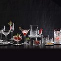Een collectie glazen met geometrische patronen, waaronder champagneglazen, cocktailglazen en schaaltjes met fruit.