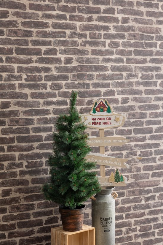 Kerstboom met bruine pot, naast een melkbus en een houten bord met kerstteksten.
