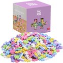 Een doos met Plus Plus Mini pastelkleurige bouwstenen en een hoopje van de stenen ernaast.